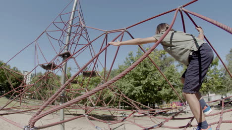 Tracking-shot-of-boy-climbing-rope-attraction-on-playground